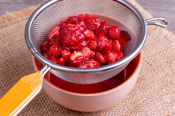 Slices of strawberries with sugar on a sieve