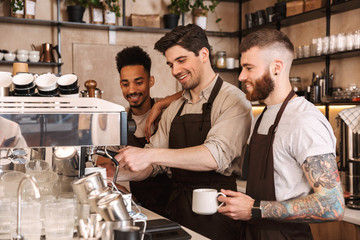 Fototapeta na wymiar Three cheerful male baristas standing at the coffee shop