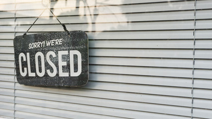 open and closed sign in the window with blind shade background
