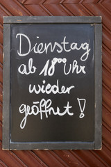 Chalkboard on gate of business with inscription in german language