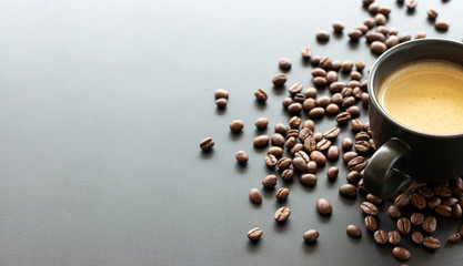 hot espresso and coffee bean on black table with soft-focus and over light in the background. top view