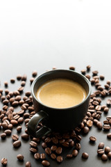 hot espresso and coffee bean on black table with soft-focus and over light in the background. top view