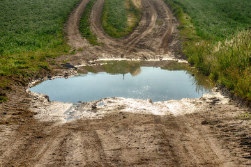 Large puddle of water on a gravel road