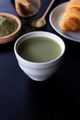 matcha green tea latte on black table with soft-focus and over light in the background