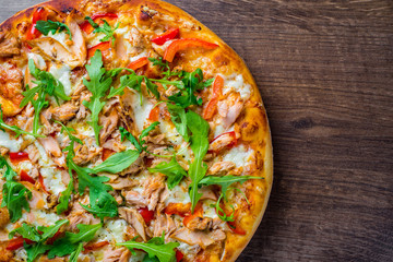 Pizza with Mozzarella cheese, salmon fish, tomato sauce, pepper. Italian pizza on wooden table background