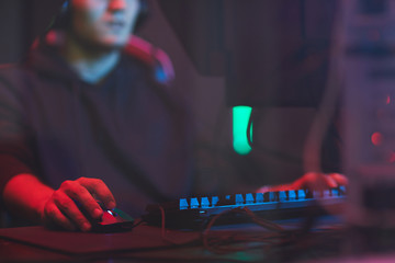 Close-up of busy man sitting at table with wires and using computer mouse while playing video game © Seventyfour