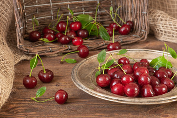 Ripe cherries in an old plate on a wooden background