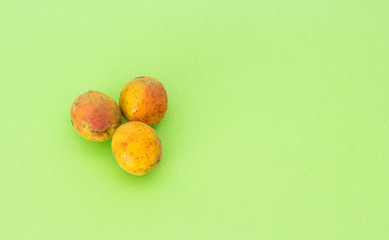 Three ugly apricots on a green background