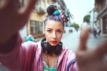 Fotobehang Playful cool funky hipster young girl with headphones and crazy hair taking selfie on street © DanRentea