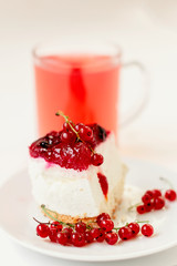 piece of souffle cake with sprigs of red currant on the background of behind juice in a cup
