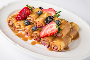 Dessert. Sweet pancakes with jam, caramel, fruit and berries. Banquet festive dishes. Fine dining restaurant menu. White background. 