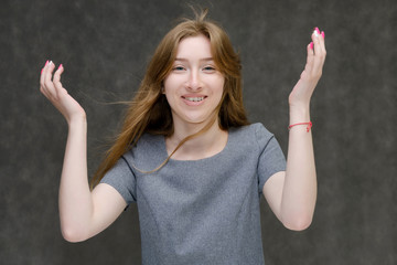 Portrait below the chest of a young pretty brunette girl woman with beautiful long hair on a gray...