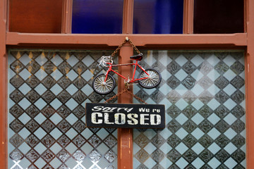 Sign sorry we are closed in front of the door of a store in town. Hanging information about work...