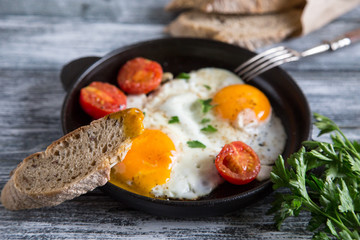 Fried egg. Close up view of the fried egg on a frying pan with cherry tomatoes and parsley