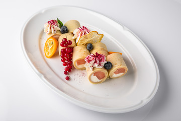 Pancakes rolls stuffed with salmon, spinach, Philadelphia cheese. Banquet festive dishes. Gourmet restaurant menu. White background.