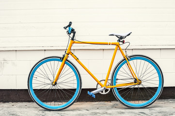 Fototapeta na wymiar Old yellow fixed gear bicycle on white wall background