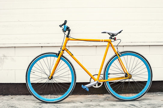 Old yellow fixed gear bicycle on white wall background