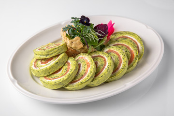 Roll of salmon and spinach. Delicate roll stuffed with fish, vegetables and herbs. Banquet festive dishes. Gourmet restaurant menu. White background.