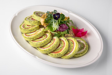 Roll of salmon and spinach. Delicate roll stuffed with fish, vegetables and herbs. Banquet festive dishes. Gourmet restaurant menu. White background.