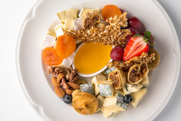 Luxurious cheese plate of different types of cheese: camembert, dorblu, parmesan, cheddar, with honey, caramel, berries. Banquet festive dishes. Gourmet restaurant menu. White background.