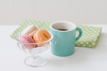 白い木目の板のに置かれたマカロンとコーヒー