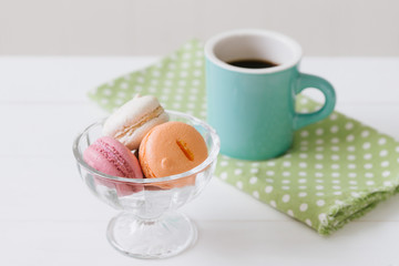 白い木目の板のに置かれたマカロンとコーヒー