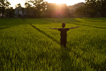 Asian Man Stretches in the Rice Fields at the Sunset