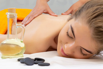 Obraz na płótnie Canvas Spa hot stone massage. Attractive beautiful girl lying on massage bed in spa salon. Spa aroma therapy and beauty treatments concept