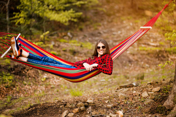 Happy lifestyle concept. Beautiful carefree woman in sunglasses in forest being happy outdoors while rest on hammock. positive attitude.