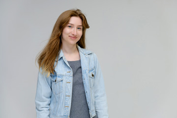 Portrait to waist of a young pretty brunette girl woman with beautiful long hair on a white background in a jacket from jeans. He talks, smiles, shows his hands with emotions in various poses.