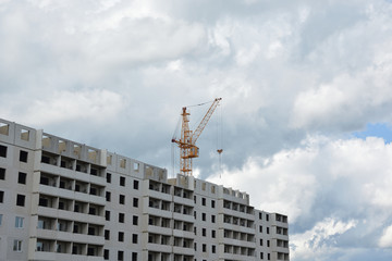 Construction of prefabricated houses. Crane and house against the blue cloudy sky. Construction. Summer