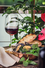  cooked mussels on a wooden board with a glass of wine