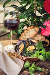  cooked mussels on a wooden board with a glass of wine