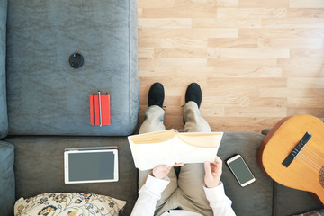 Caucasian man reading a book studying in the living room. Overhead shot from above and empty copy space for Editor's text. © JuanCi Studio