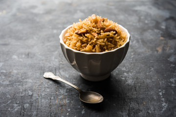 Traditional Jaggery Rice or Gur wale chawal in Hindi, served in a bowl with spoon. selective focus