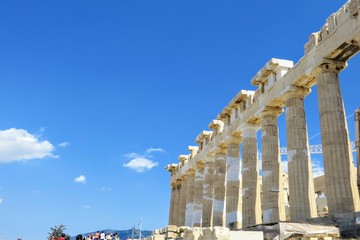 Obraz premium An interesting view of the Parthenon columns facing a blue sky atop the Acropolis in Greece. The parthenon has Doric columns made of marble extending around the periphery of the entire structure
