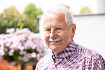 portrait of senior, old men smile and is relaxed in his garden with a white wand