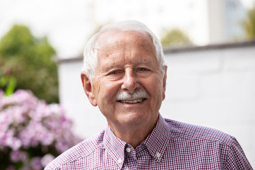 portrait of senior, old men smile and is relaxed in his garden with a white wand