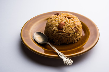 Traditional Jaggery Rice or Gur wale chawal in Hindi, served in a bowl with spoon. selective focus