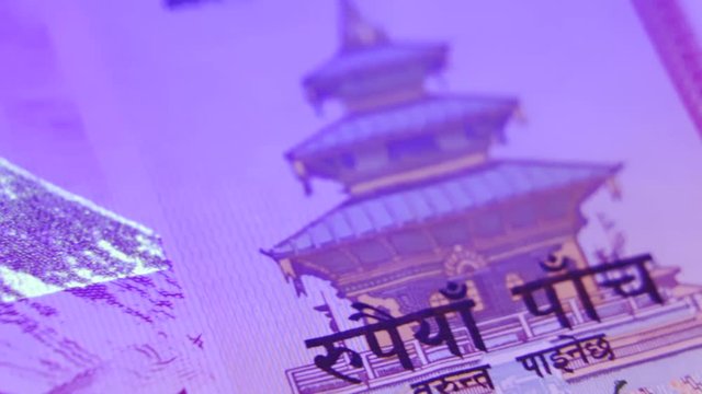 Shiny reflective nepalese rupee currency notes under ultraviolet blacklight, close up macro