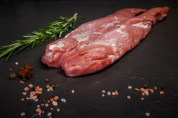 two long pieces of raw marbled meat with green rosemary
