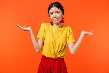 Confused displeased young woman posing isolated over orange wall background.