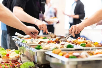 Fotobehang Hands picking up food from buffet catering table at the party. © zphoto83