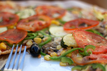 Close-up of vegetarian pizza with tomato sauce, cheese, tomatoes, zucchini, mushrooms, pepper and corn. Selective focus.