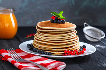 Pile of homemade baked classic american pancakes with fresh berries and green mint for delicious breakfast