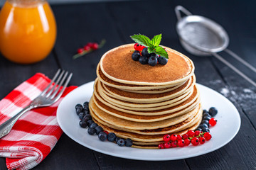 Pile of homemade tasty pancakes with fresh berries and green mint for delicious breakfast