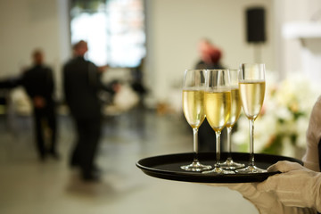 A tray with three glasses of champagne. Waiter holding a tray with a champagne glass