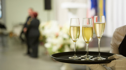 A tray with three glasses of champagne. Waiter holding a tray with a champagne glass