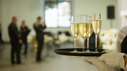 A tray with three glasses of champagne. Waiter holding a tray with a champagne glass