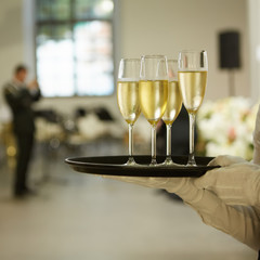A tray with three glasses of champagne. Waiter holding a tray with a champagne glass